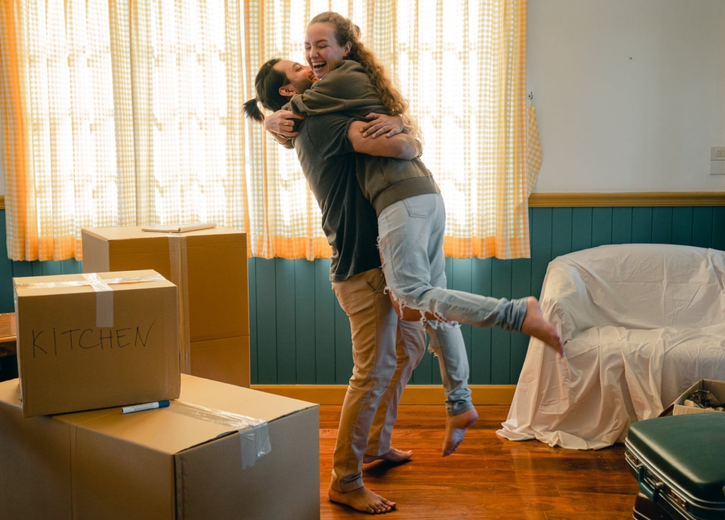 cheerful couple hugging and unpacking carton boxes